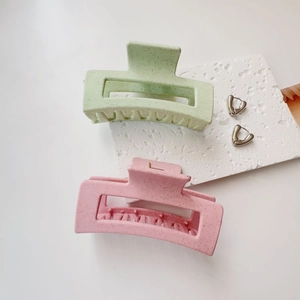 Detail of light green and pink matte hair claws with sesame texture and hollow rectangle design
