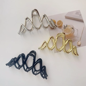 Three wavy metal hair claw clips in gold, silver, and black on a white background