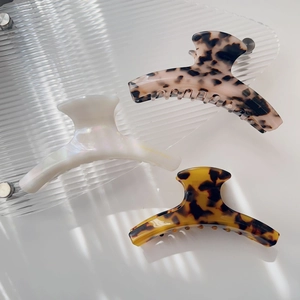 Three acetate hair claws in pearl white, leopard print, and tortoiseshell patterns