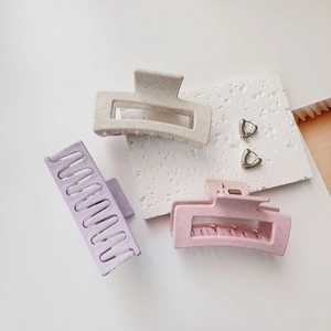 Detail of matte hair claws in lavender and cream with speckled texture and silver heart earrings