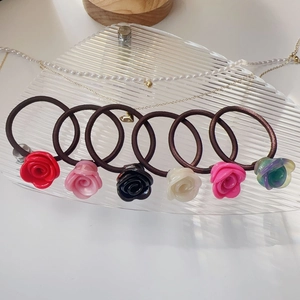 Détail de 6 chouchous fleurs de rose en acétate coloré sur un plateau en verre