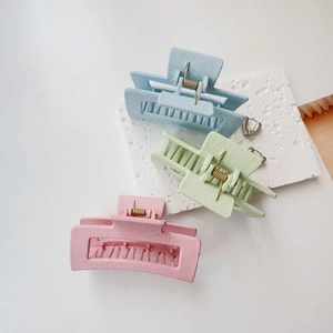 Three matte hair claw clips in pastel pink, green, and blue on a stone display