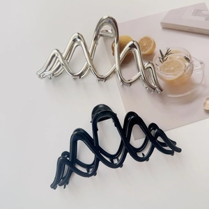 Close-up of wavy metal hair claws in glossy silver and matte black for hair styling