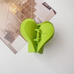 Dettaglio della molletta a cuore verde opaco con robusta molla in metallo argentato