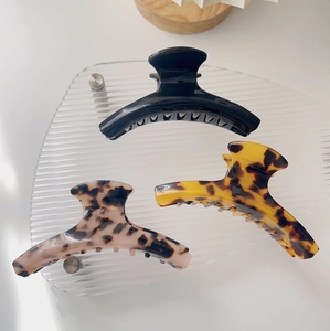 Three acetate hair claws in black, yellow, and pink leopard print on acrylic tray