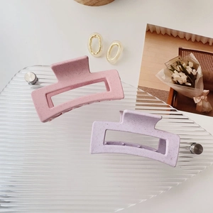 Minimalist rectangle matte hair claw clips in pink and purple colors on a textured tray