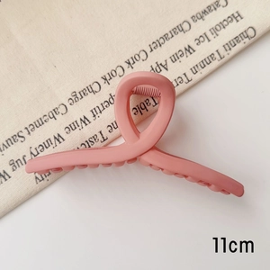 Détail d'une pince à cheveux mate rose de 11cm avec texture givrée sur tissu vintage