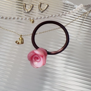 Détail de l'élastique à cheveux rose en résine sur un plateau en verre avec bijoux