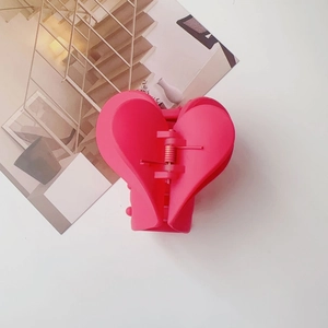 Dettaglio della pinza per capelli a cuore rosa opaco con robusta molla interna in metallo