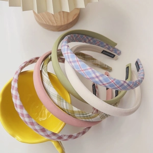 Detailed view of handmade cream plaid and solid fabric headbands on a yellow bowl