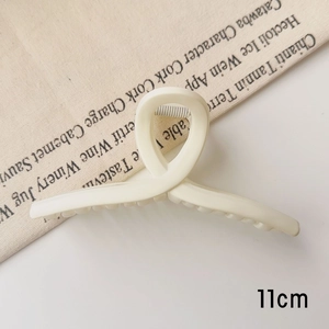 Détail de la pince à cheveux blanc crème mat de 11cm avec un design croisé minimaliste