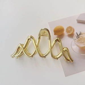 Detail of large golden wavy hair claw clip with strong metal spring for thick hair