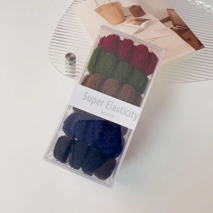Detailaufnahme von hochelastischen Haargummis in verschiedenen dunklen Farben in Box