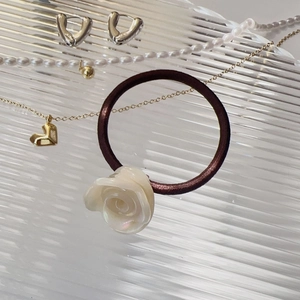 Détail d'un élastique à cheveux marron élégant orné d'une fleur de rose blanche nacrée