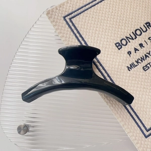 Macro detail of glossy black acetate hair claw with fine handmade engraving