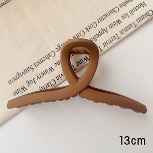 Gros plan détaillé d'une pince à cheveux mate marron chaud de 13 cm dans un décor naturel