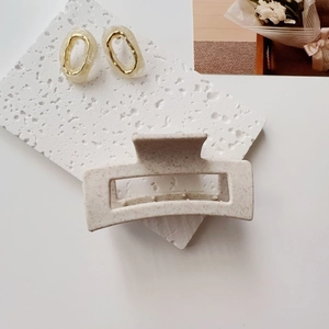 Detail of a beige speckled square hair claw clip and gold-tone resin earrings set