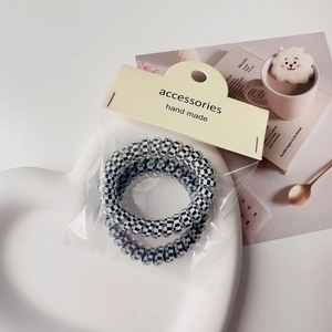 Detail view of black and white checkered spiral hair ties in premium minimalist packaging