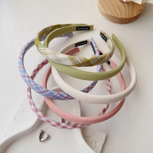 Detail of stacked handmade fabric headbands in plaid and pastel colors on a tray