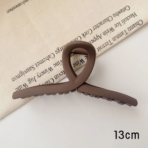 Détail de la pince à cheveux mate marron chocolat de 13cm avec design à boucle croisée