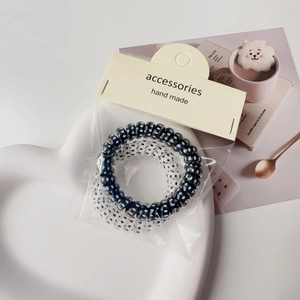 Detail of black and transparent polka dot spiral hair ties in a heart tray