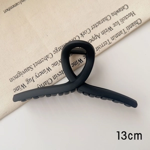 Gros plan d'une pince à cheveux noire mate de 13cm avec un design croisé épuré