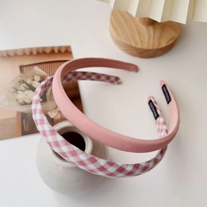 Detail of pink and checkered cream plaid headband set displayed on white ceramic