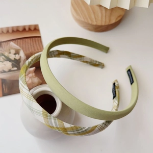 Close-up of light green and plaid fabric headbands set against a soft lifestyle backdrop