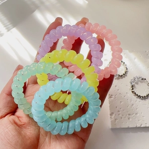 Pastel color telephone cord hair ties in hand featuring a traceless spiral design