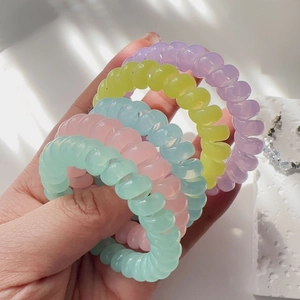 Close-up of five pastel spiral hair ties in soft purple, yellow, pink, blue and green