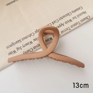Détail d'une grande pince à cheveux mate café de 13 cm avec une conception à dents croisées