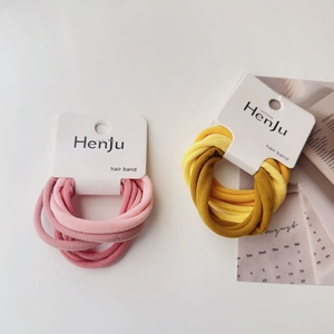 Detail of high-elasticity hair bands in pink and yellow tones with textured fabric finish