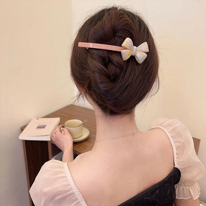 Creamy acetate bow hair clip with marble texture on elegant woman's ponytail
