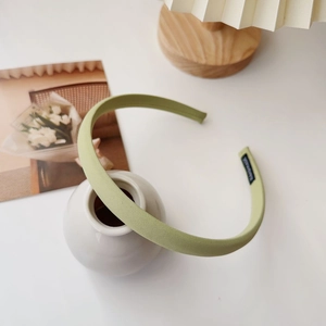 Detail of light green fabric headband showing fine texture and inner brand label