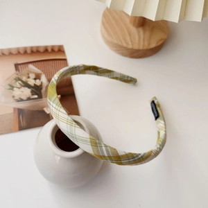 Close-up of yellow and green plaid fabric headband with a black handmade label detail
