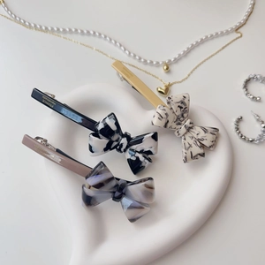 Three acetate bow hair clips in marble patterns displayed on a white heart-shaped tray