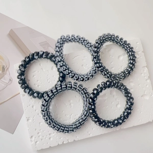 Close-up of five spiral hair ties with checkered and star patterns on stone