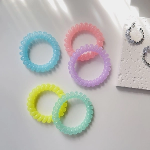 Detailed macro view of multi-colored pastel spiral hair ties on a white textured surface