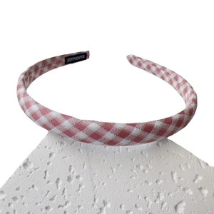 Pink and white gingham fabric headband with handmade tag on white stone display