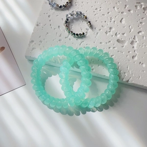 Detail of mint green spiral telephone wire hair ties and silver C-shaped rhinestone earrings