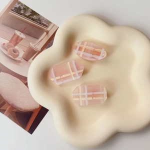 Vue détaillée de trois pinces à cheveux à carreaux roses sur un plat en céramique crème