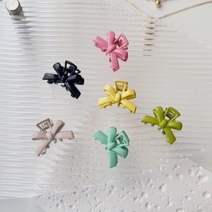 Set of six colorful matte ribbon bow hair clips displayed on a modern textured background