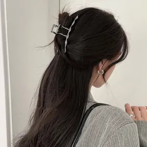 Detailed view of silver liquid metal hair claw clip and matching rings on model