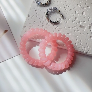 Close-up of pink spiral hair ties and silver crystal earrings on a stone tray