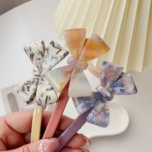 Close-up of marble texture acetate bow hair clips in pastel yellow, pink, and purple colors