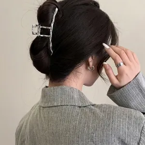 Large silver alloy claw clip with wavy texture for hair styling on woman's head