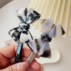 Close-up of bow hair clips with marble texture acetate and sleek black metal springs