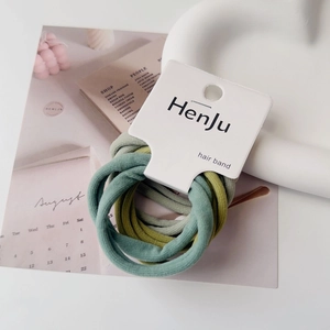 Close-up of minimalist green hair band set on a decorative white wave texture tray