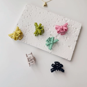Set of six matte bow hair clips in vibrant macaron colors on a white marble surface