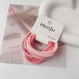 Detailed view of pink elastic hair bands with a brand tag on a cream decorative plate